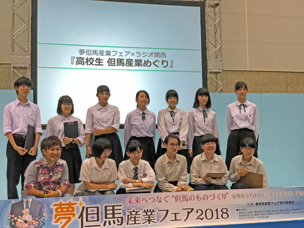 写真は昨年に開催された「夢但馬産業フェア2018」より、「高校生但馬産業めぐり」に出演した高校生と、番組コーナーのスペシャルサポーターを務めるシンガーソングライターの門松良祐（写真左下）