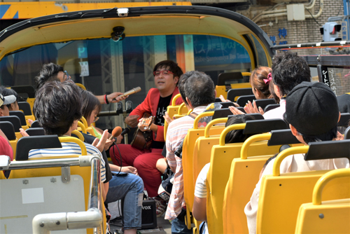 最後はクマガイタツロウがスカイバス車内でギターを弾きながら熱唱。参加者とともにイベントは最後まで盛り上がった（写真：ラジオ関西）