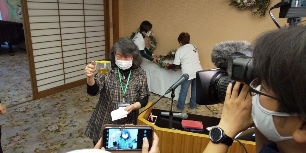 搾油したオリーブ油を掲げる中西テツ神戸大学名誉教授（写真：ラジオ関西）