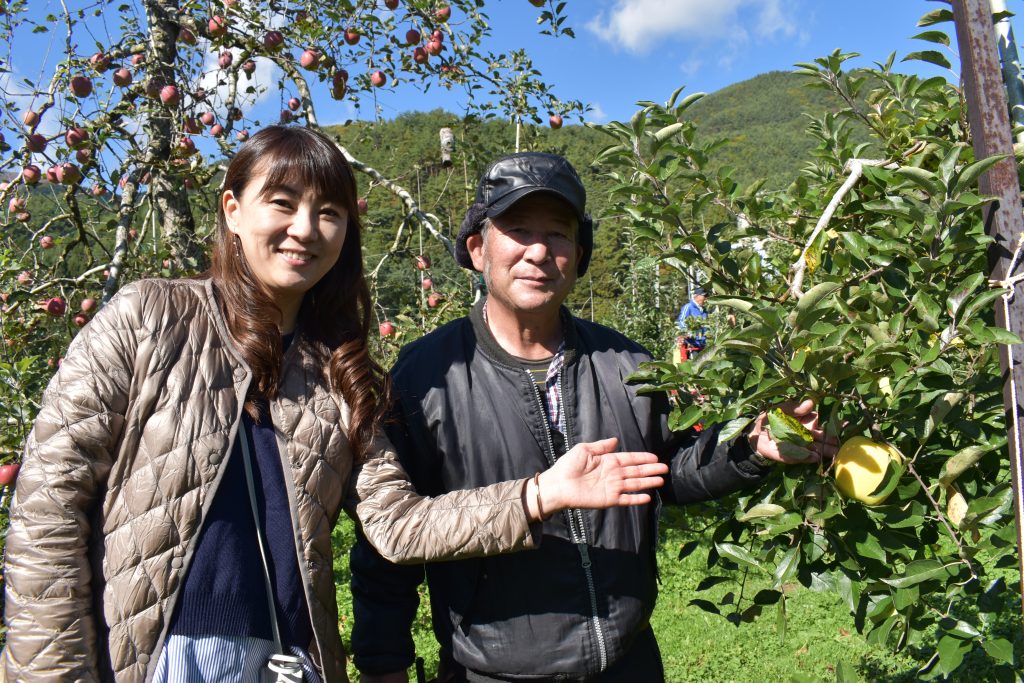 安曇野観光果樹園の布山久義社長（右）イチオシの「はるか」を前に。左はナビゲーターの慶元まさ美さん