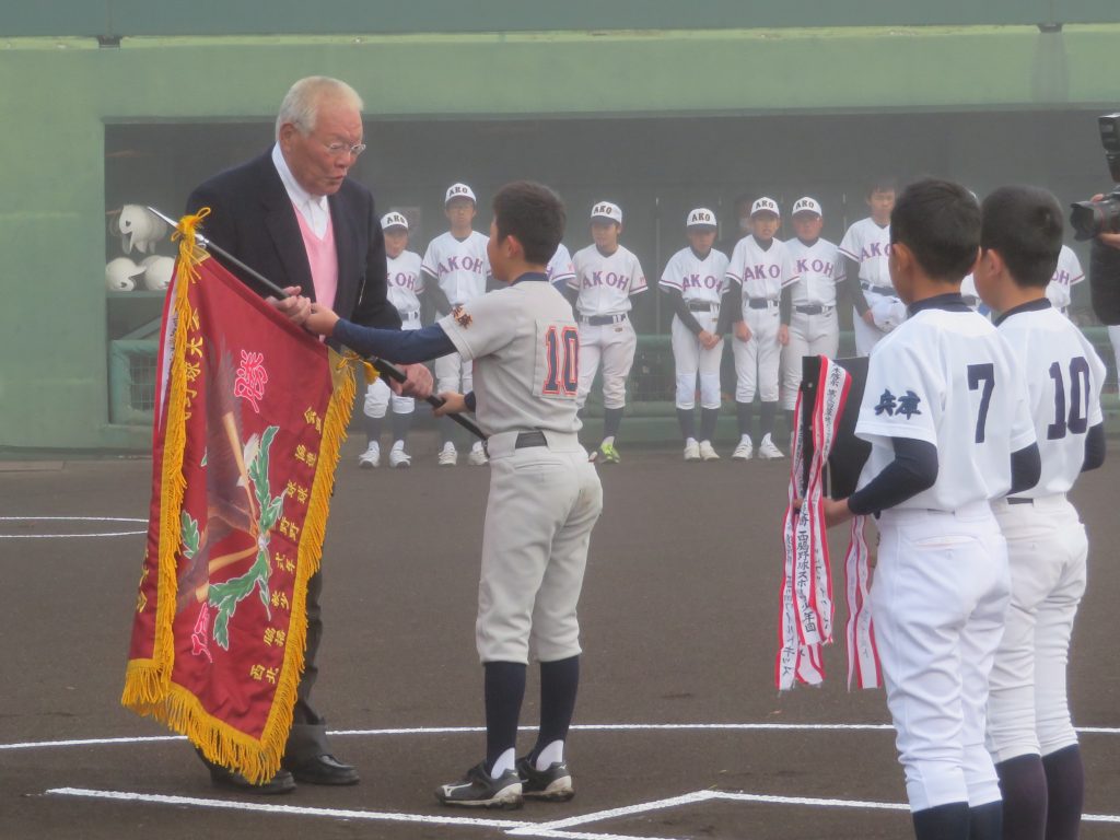 大会初日、優勝旗の返還を受ける鈴木啓示さん＝西脇市の西脇公園野球場