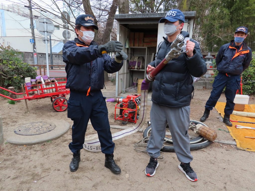 放水ポンプの使い方を教わる留学生（右）