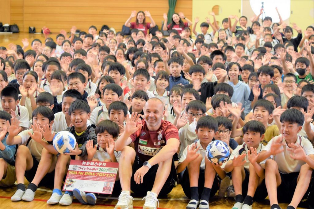 舞多聞小学校6年生の児童たちと記念撮影におさまるアンドレス・イニエスタ選手（写真：ラジオ関西）