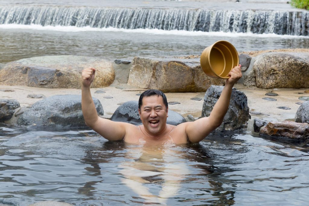 河原風呂に入る、とにかくあかるい安村さん（写真提供：鳥取県）