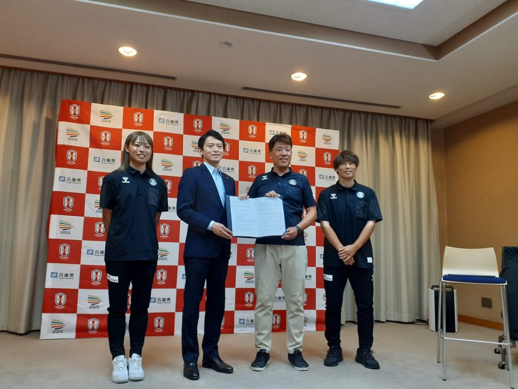 包括連携協定調印式で　 左から：INAC神戸レオネッサ・井手ひなた選手、齋藤元彦兵庫県知事、安本卓史・アイナックフットボールクラブ（株）代表取締役社長、高瀬愛実選手