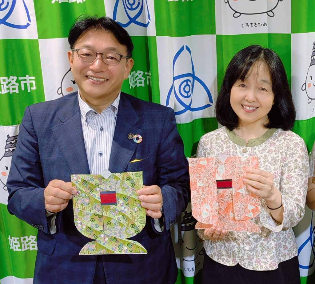 「七夕さんの着物」を手に持つ、日本玩具博物館・学芸員の尾崎織女さん（右）とパーソナリティの清元秀泰姫路市長 （左）