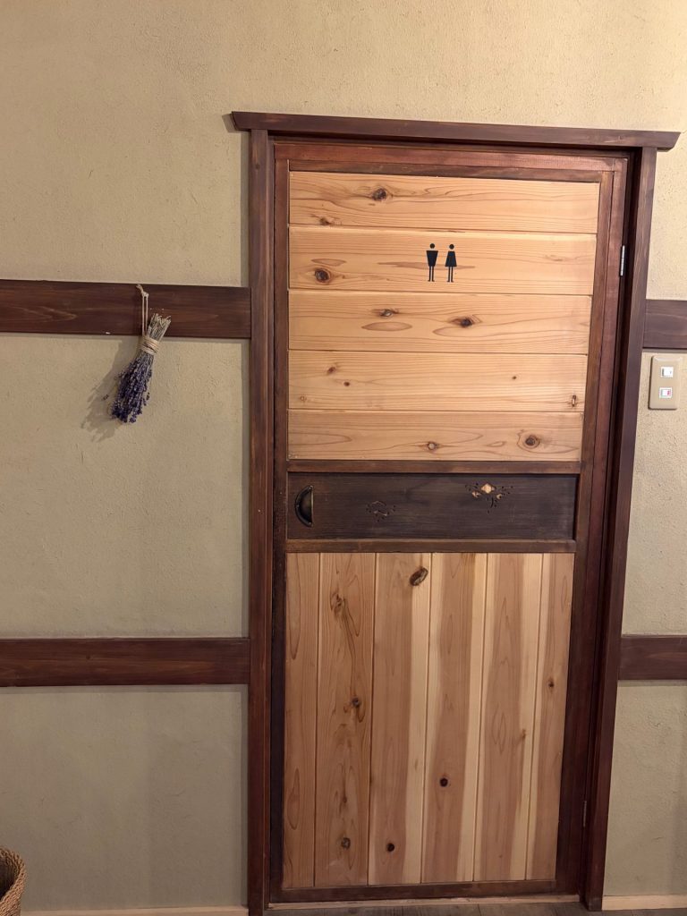 母屋の扉を再利用したトイレの扉