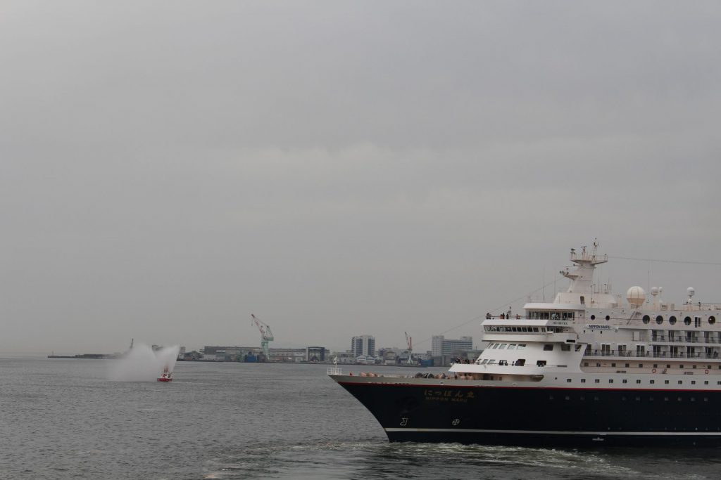 にっぽん丸と歓送放水をする神戸市消防艇（左奥）